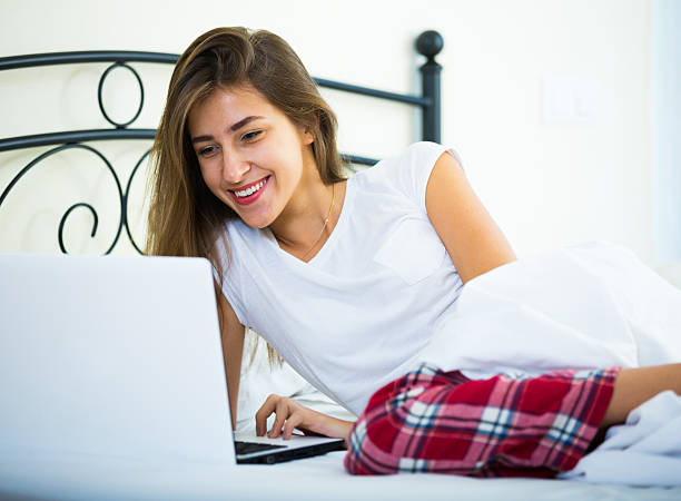 istock Cheerful student girl studing with laptop in bed 492550314