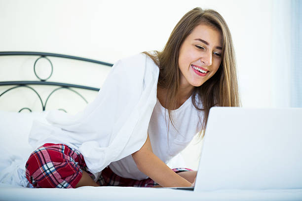 istock Cheerful student girl studing with laptop in bed 492550394