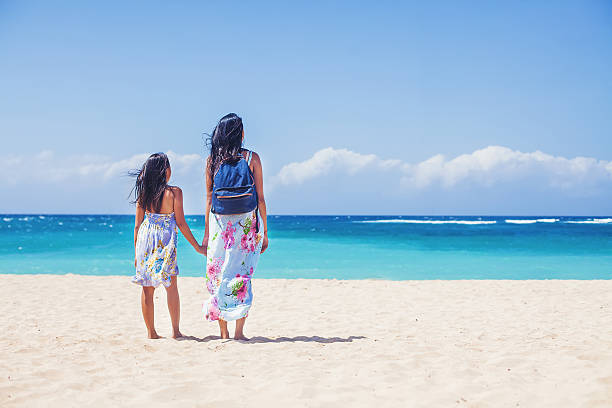 istock two asian girls holding hands on a beach 492551108