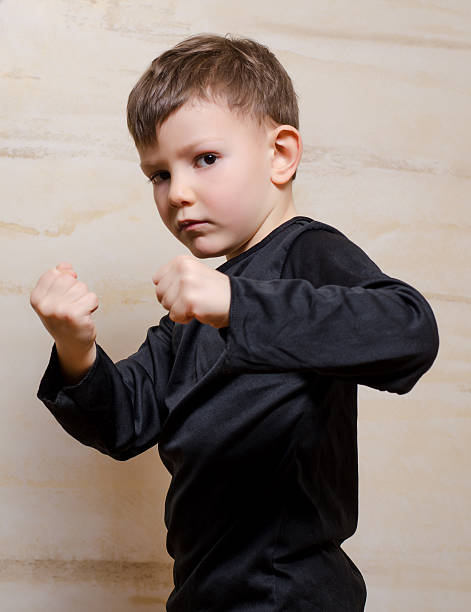 istock Serious Fighter Kid Posing with Closed Fists 492551584