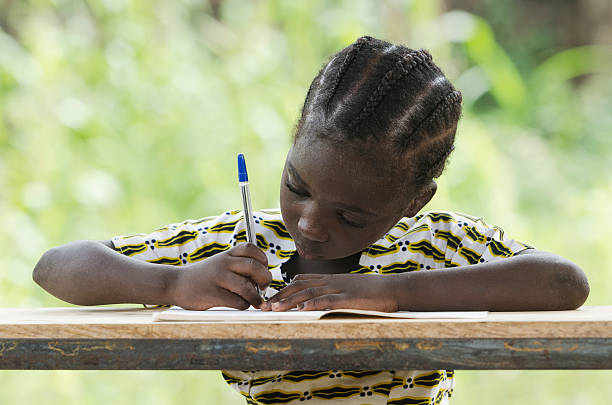 nur ein mädchen: kleine afrikanische mädchen schreiben in ihre arbeitsmappe - child thinking writing little girls stock-fotos und bilder