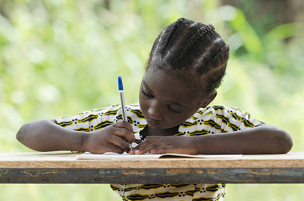 só uma rapariga: pequena menina africano em seu caderno de escrita - child thinking writing little girls imagens e fotografias de stock