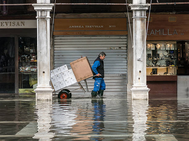 Man pulls his trolley through flood waters in Venice stock photo