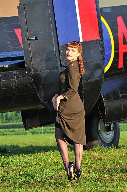 Army pinup girl with WWII bomber sexy woman in an army dress standing next to a WWII bomber 40s pin up girls stock pictures, royalty-free photos & images