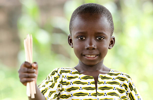 Light Smile on African Black Boy Little African boy smiling whilst holding up a bunch of pencils for an educational symbol for Africa. Beautiful education background with copy space. sad african child drawings stock pictures, royalty-free photos & images
