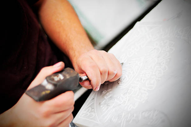 istock Manufacturer carving arabic script on marble plate on market, Morocco 492573135