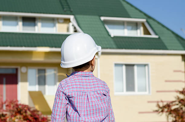 istock Boy Wearing Hard Hat Standing in front of House 492573314