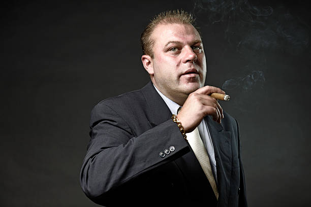 istock Gangster mafia man in suit with tie smoking a cigar. 492574703