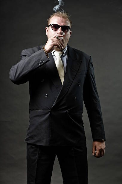 istock Gangster mafia man in suit with sunglasses smoking a cigar. 492575247