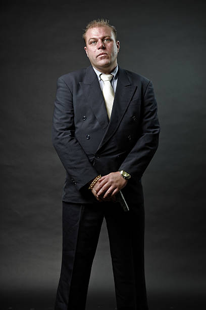 istock Gangster mafia man in suit with tie holding a gun. 492576271
