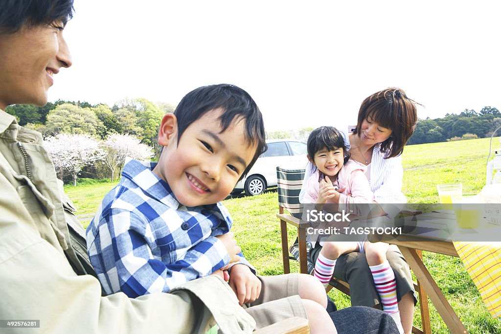 Famiglia godendo picnic nella prateria - Foto stock royalty-free di Abbracciare una persona