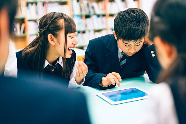 Japanese students playing a fun digital tablet game Japanese Students playing a Fun digital tablet game in the school library. child japanese culture japan asian ethnicity stock pictures, royalty-free photos & images