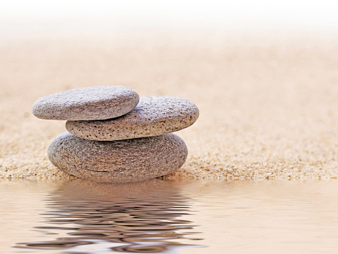 Zen stone stack and sand, water reflections