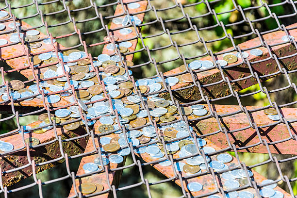 Japanese coins on a wishing well Lots of Japanese Yen currency coins on a grill/grid over a wishing well. thomas wells stock pictures, royalty-free photos & images