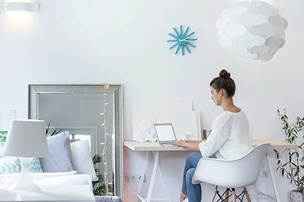 Girl working on laptop in white room