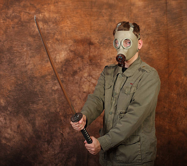 istock Man with gas mask, katana sword on brown batik  background 492584588