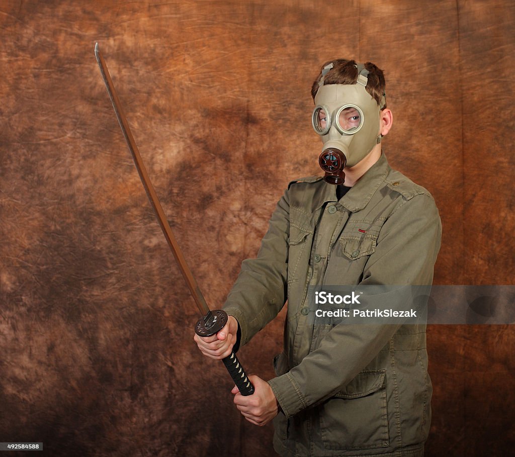 Man with gas mask, katana sword on brown batik  background Man with gas mask and  katana sword on brown batik background Gas Mask Stock Photo