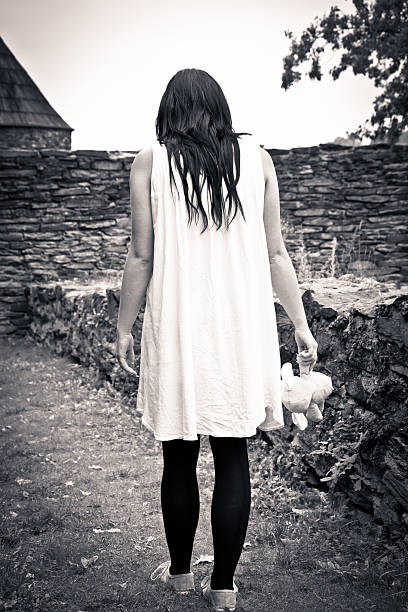 A mentally disturbed young woman is walking in the fog with a teddy bear