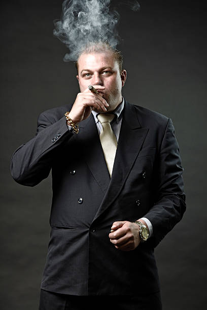 istock Gangster mafia man in suit with tie smoking a cigar. 492594601