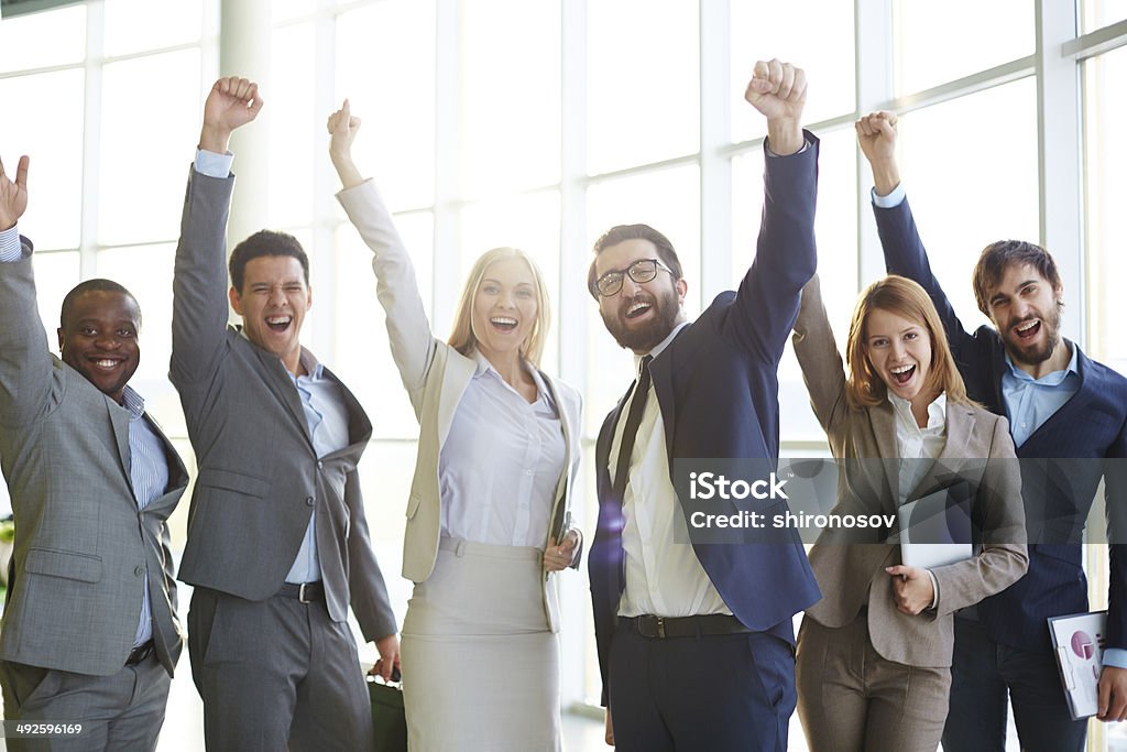 Excited co-workers Group of ecstatic business partners looking at camera with raised arms Business Stock Photo