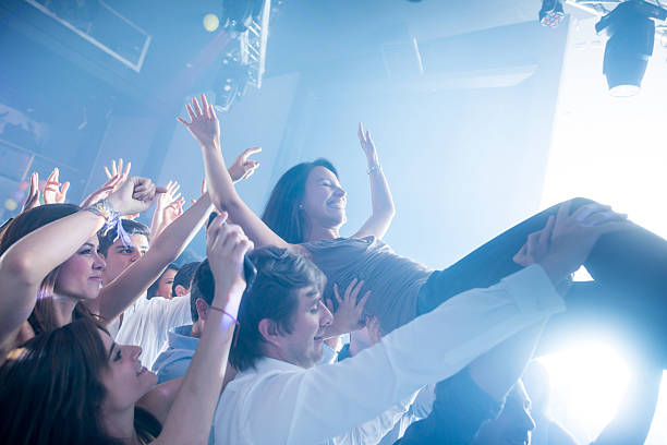Woman diving into the crowd at a concert Happy woman diving into the crowd at a concert and having a lot of fun mosh pit stock pictures, royalty-free photos & images