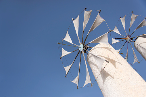 Tilted image of two white greek windmills against a clear blue sky on the island of Crete.