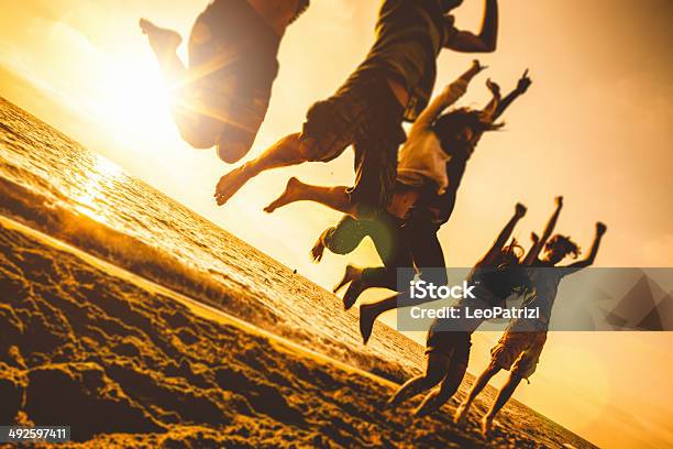 Group Of Friends Jumping On The Beach At Dusk Stock Photo - Download Image Now - Activity, Adult, Adults Only