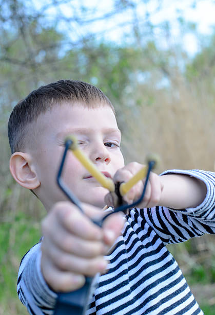 istock Young Boy Aiming Sling Shot at Camera 492597670