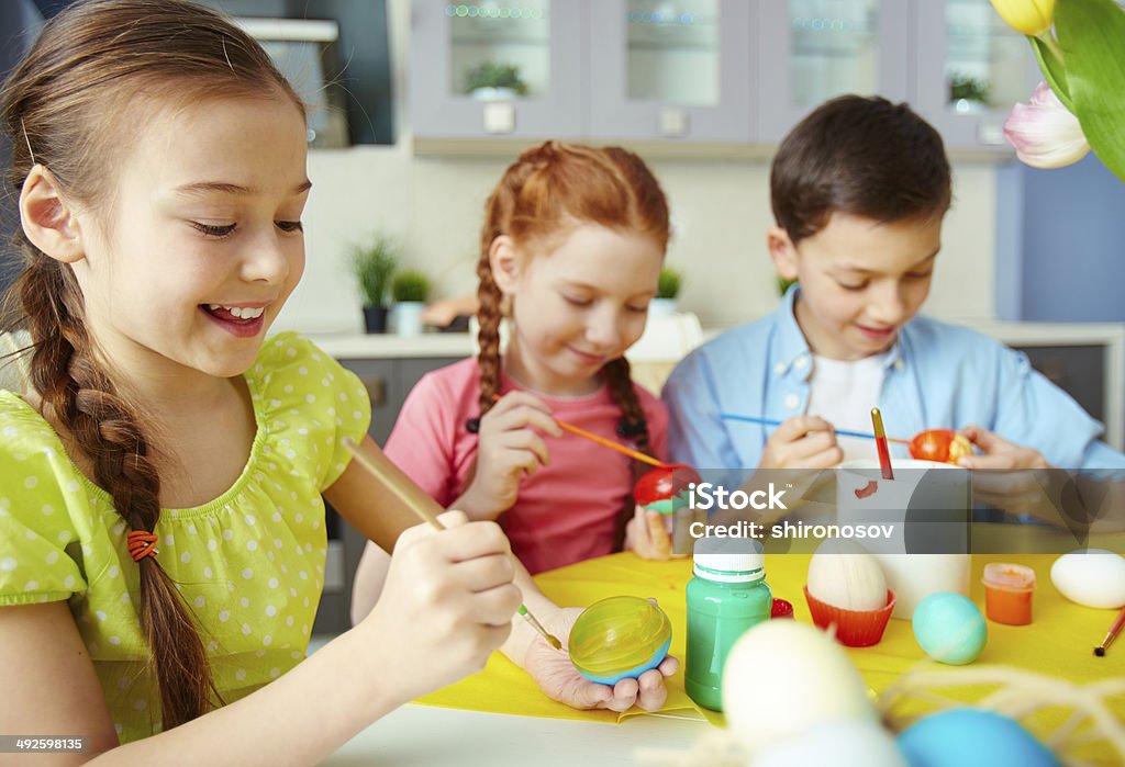 Concentrated on Easter creativity Schoolchildren painting eggs for Easter April Stock Photo