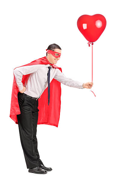 istock Man in superhero costume holding a red balloon 492599349