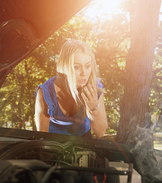 istock Vehicle breakdown: pretty blonde driver eyes smoking engine, very worried 492601166