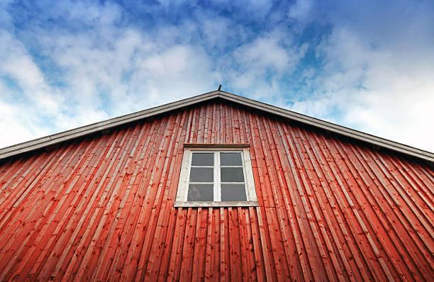 istock Red wooden wall with window above blue cloudy sky 492601386