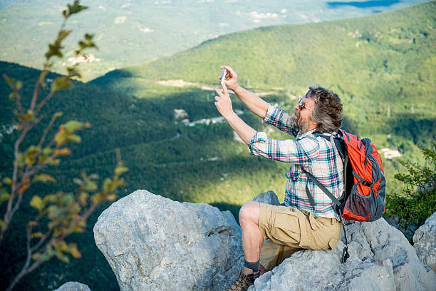 istock Senior Man Taking Selfie on top of a Mountain 492608510