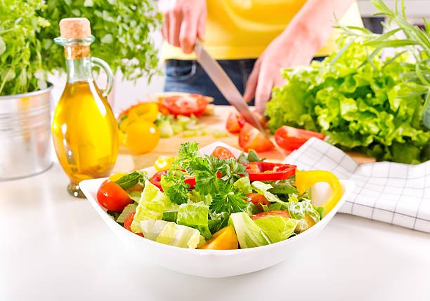 istock Female hands preparing vegetable salad in the kitchen 492608554