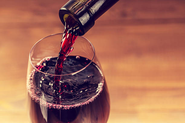 木製の背景に対してグラスに赤ワインを注ぐ - wine pouring wineglass red ストックフォトと画像