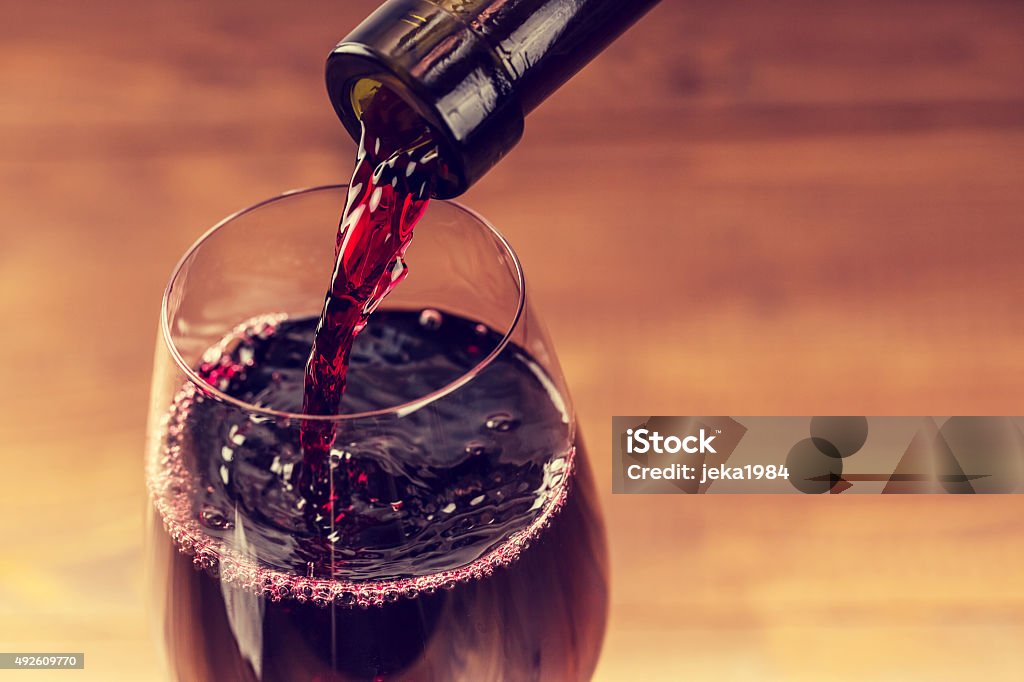 Pouring red wine into the glass against wooden background Wine Stock Photo