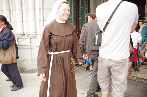 Lourdes, France - August 19, 2015: Nun walking to the chapel during here pilgrimage in Lourdes. She is very impressed. 