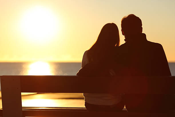 vista traseira de um casal observa o sol na praia - sun watch - fotografias e filmes do acervo