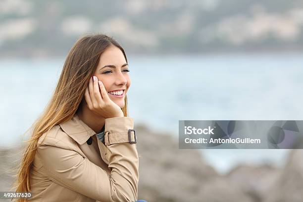 Happy Woman Thinking And Looking Away On The Sea Stock Photo - Download Image Now - 2015, Adult, Autumn