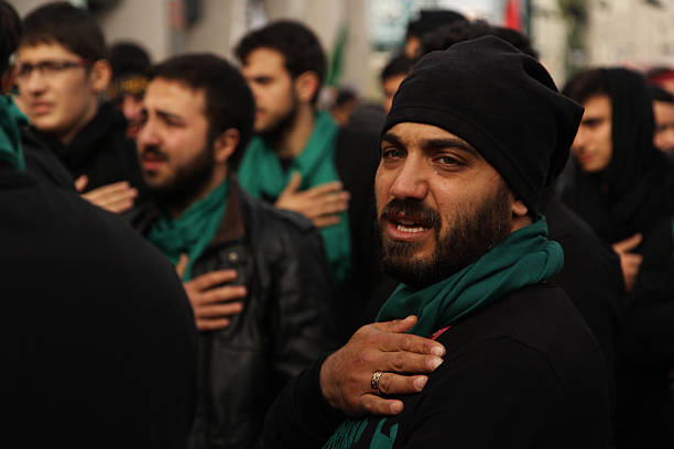 Day of Ashura Istanbul, Turkey- November 3, 2014: Group of muslim men standing in a stadium to watch the religious procession in the Day Of asura in Istanbul, Turkey. Ashura is an Islamic holiday observed on the 10th of Muharrem, the first month of the Islamic year. The word Ashura means "10" denoting the date of the holiday.  day of ashura stock pictures, royalty-free photos & images