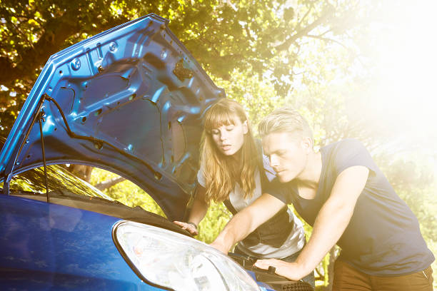 istock Worried young couple confused by broken-down car engine 492619544