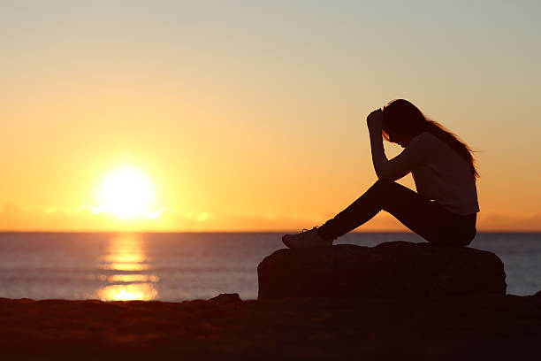 istock Sad woman silhouette worried on the beach 492619740