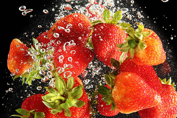 istock Strawberries falling into water at black background 492621174