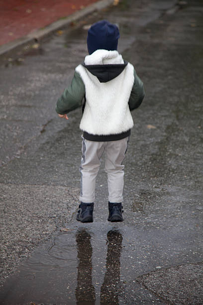 istock Child jumping in water puddle after rain. 492621612