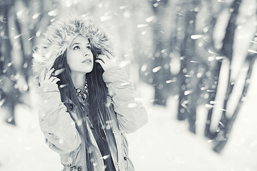 Beautiful smiling young woman in warm clothing. The concept of portrait in winter snowy weather.