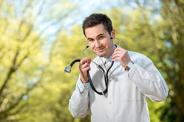 istock Young doctor listening with stethoscope on the green park background 492624607