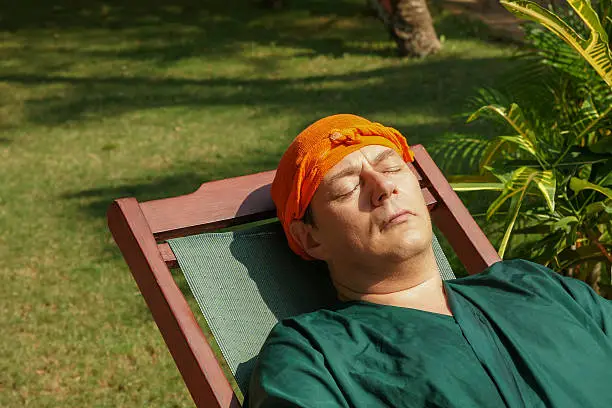 man has a rest after an ayurveda-treatment, on his head a herbal pack