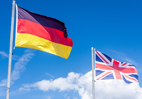 National flag of Germany and the Union flag set against a deep blue sky with white clouds