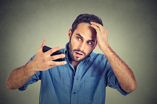 shocked man feeling head, surprised losing hair, receding hairline Closeup portrait, shocked man feeling head, surprised he is losing hair, receding hairline, bad news isolated on gray wall background. Negative facial expressions, emotion feeling dandruff men stock pictures, royalty-free photos & images