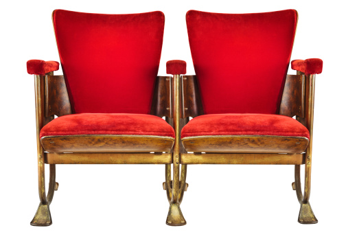 Two vintage red movie theater chairs isolated on a white background